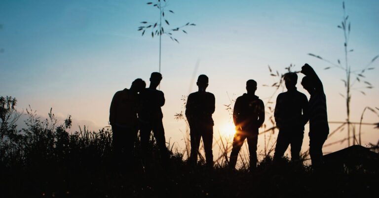 A group of friends silhouetted against the sunset, enjoying a moment in nature.